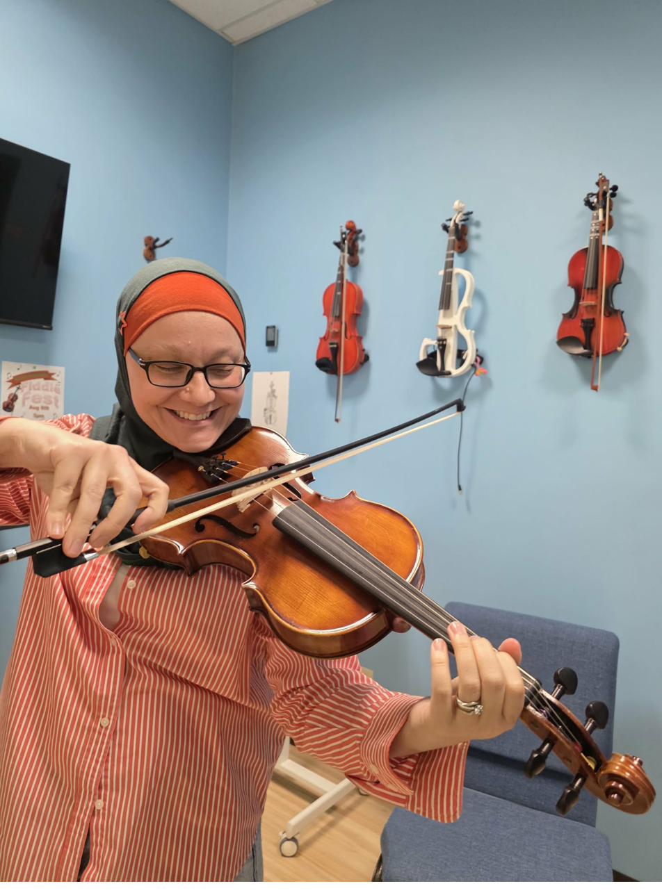 Student smiling while playing viola at Keys of Joy Studio in Lawrence, KS